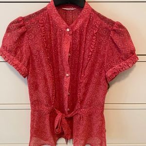 Women’s floral blouse with faux pearl buttons and ruffle trim detail.